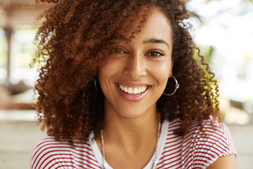 A young woman with curly hair smiling